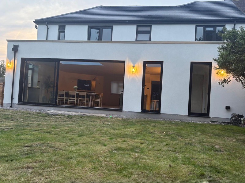 Black sliding doors across a rendered back wall at dusk