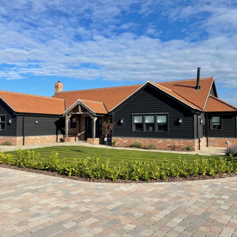 Black weatherboarded bungalow with clay tiles, an oak framed porch and a block paved driveway