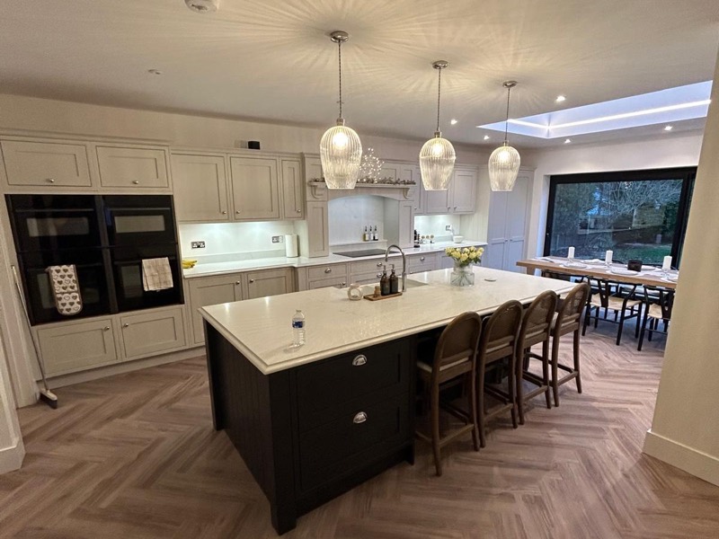 Shaker kitchen with a dark island, herringbone flooring and a roof lantern over the dining area