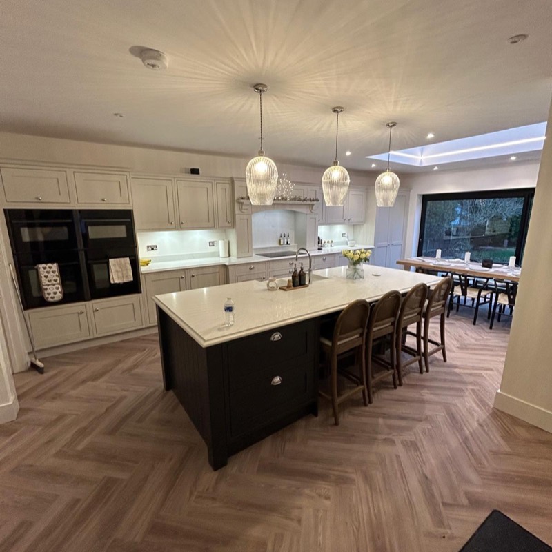 Open plan kitchen diner with a dark island, glass pendant lights and a roof lantern