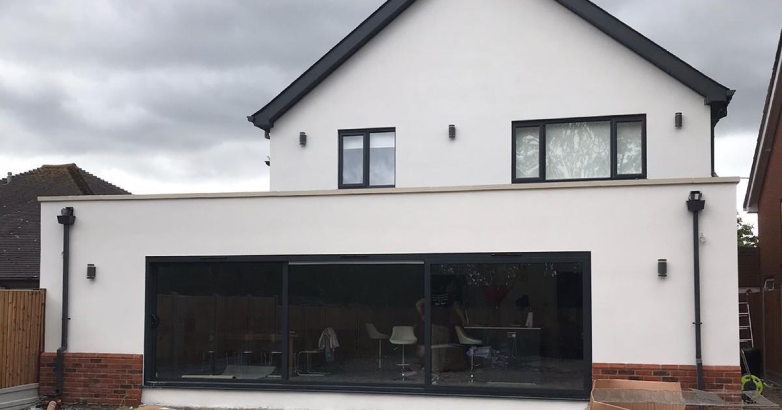 Rendered house with a flat roofed rear extension and wide black sliding doors