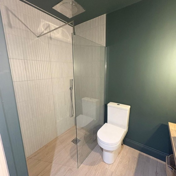 White fluted tiles and a rain shower against a green wall