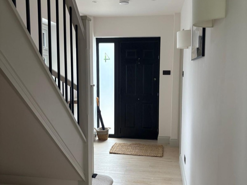 Hallway with oak flooring and a black front door