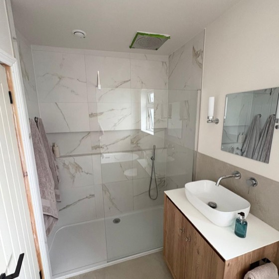 Walk-in shower and oak vanity in a marble tiled room