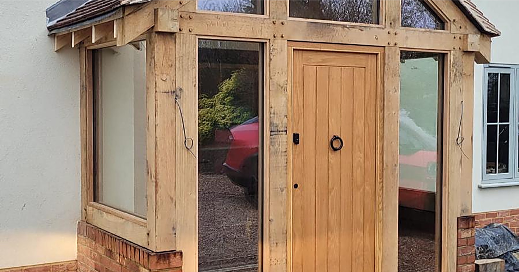 Oak framed glazed porch with a plank front door on a brick plinth