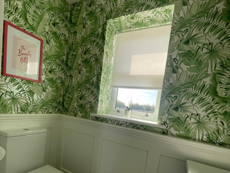 Palm print feature wallpaper above white wall panelling