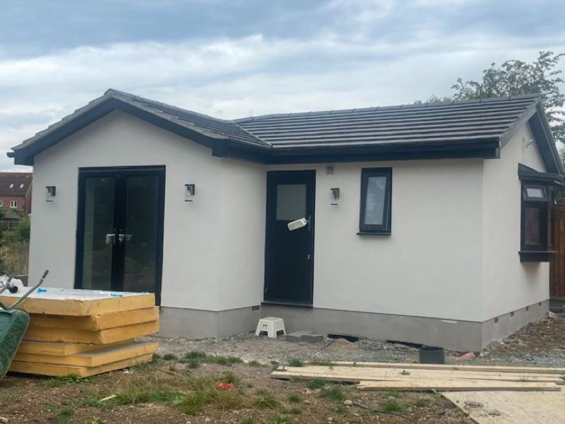 Rendered single storey building with grey windows