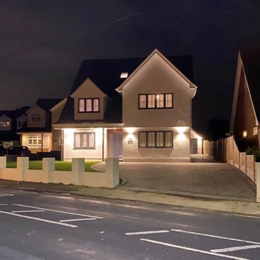 Rendered detached house lit up at night behind a rendered front wall