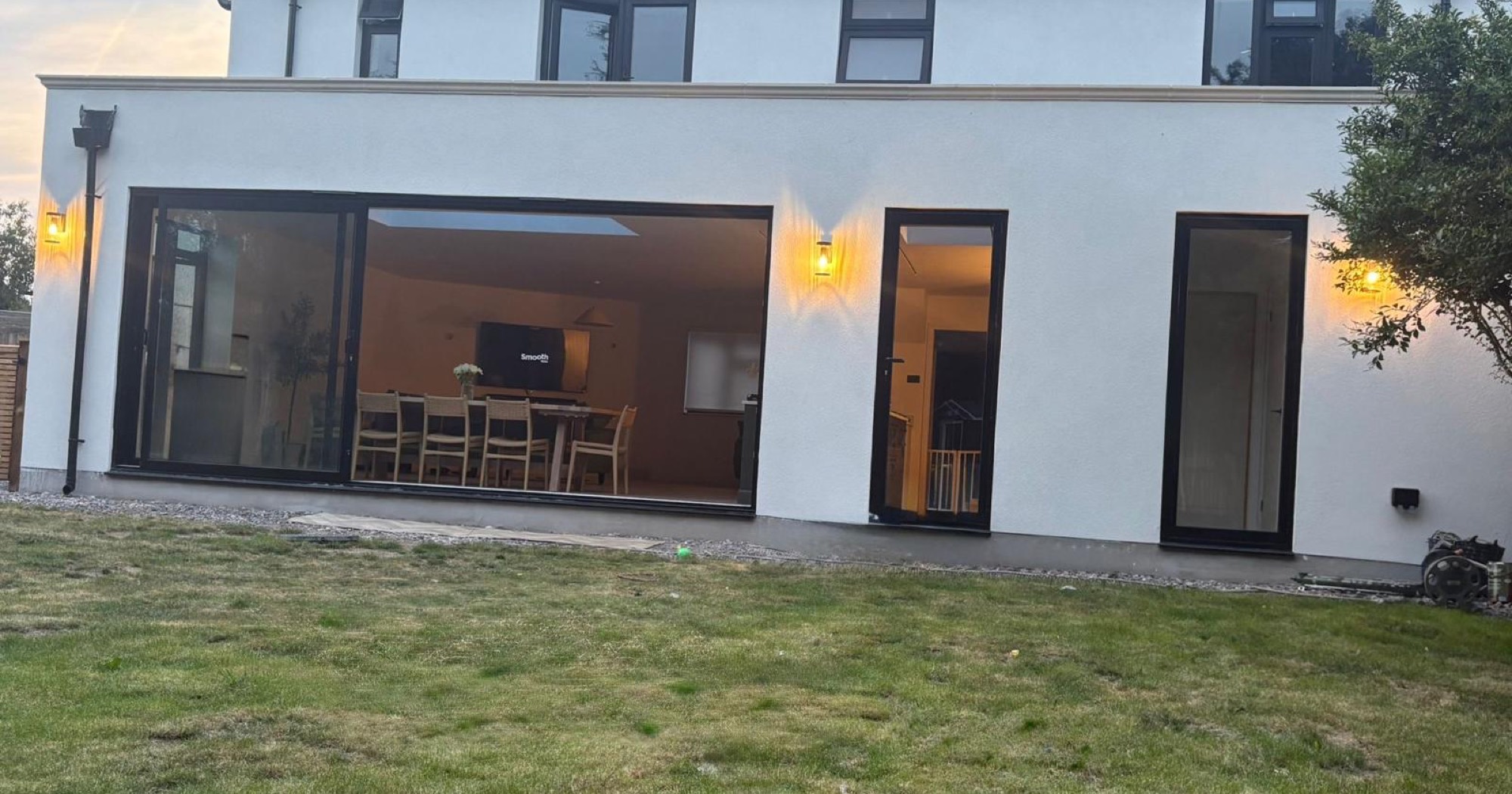 Rendered back of a house with black sliding doors at dusk