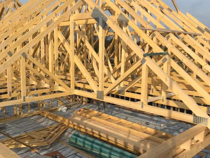 Timber roof trusses going up above a boarded floor