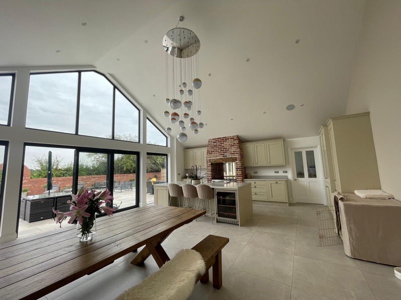 Open plan kitchen diner with an island and a statement pendant under a vaulted ceiling