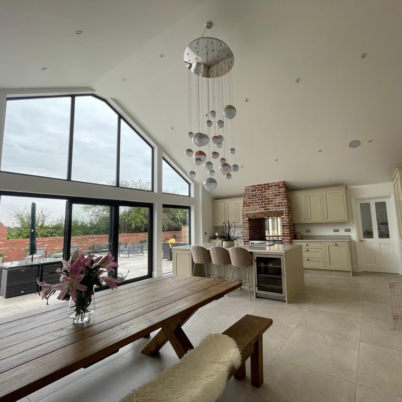 Open plan kitchen diner with a vaulted ceiling, a glazed gable and doors onto the patio