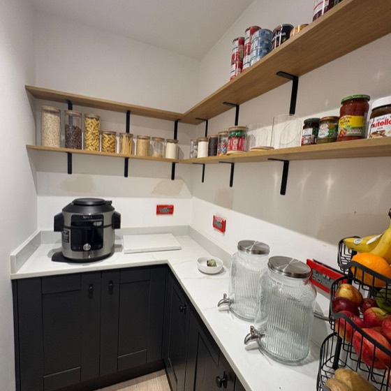 Walk-in pantry with oak shelving and white worktops