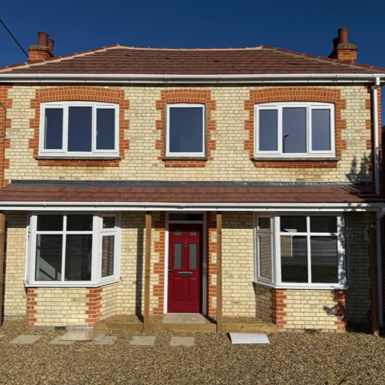 Yellow stock brick house with bay windows and a red front door